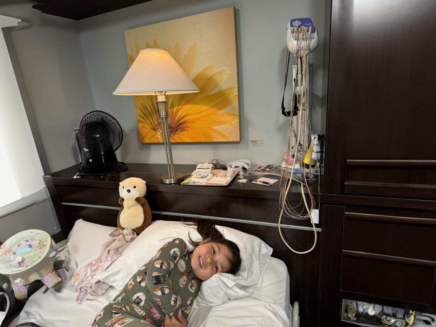 A young girl laying in bed with her teddy bear.