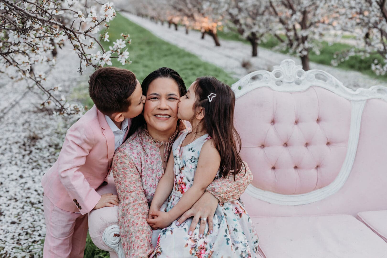 A woman and two children kissing on the cheek.