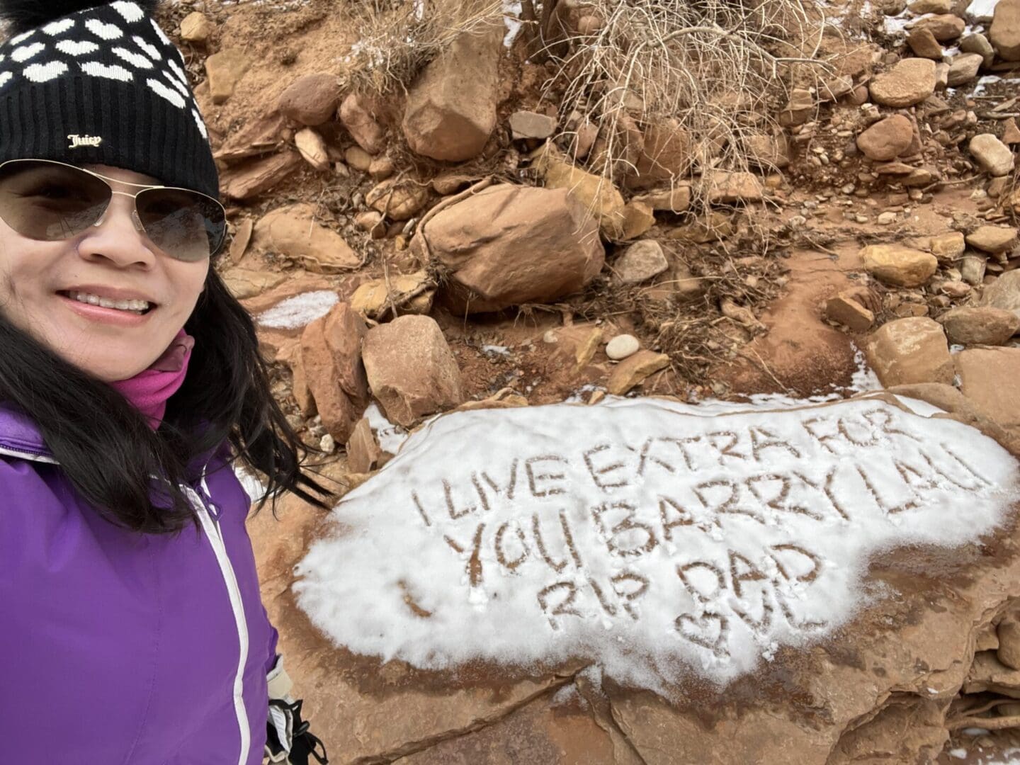 A woman standing next to a rock with writing on it.