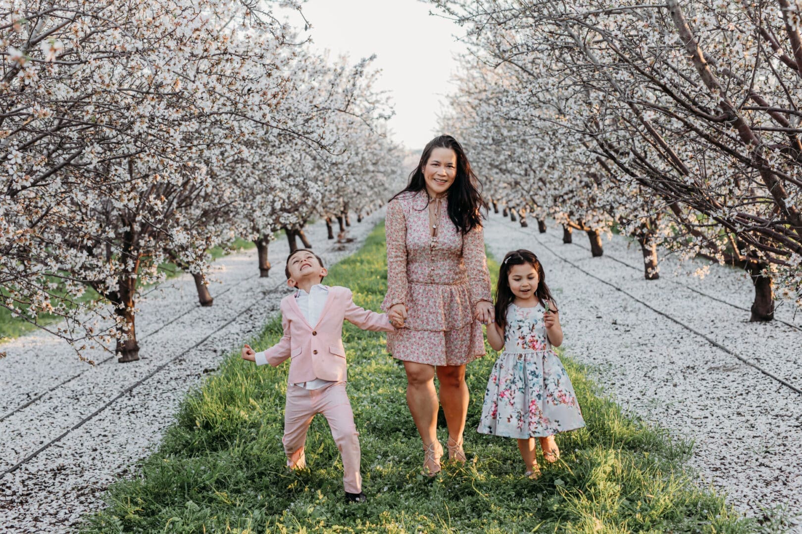 A woman and two children in the middle of an orchard.