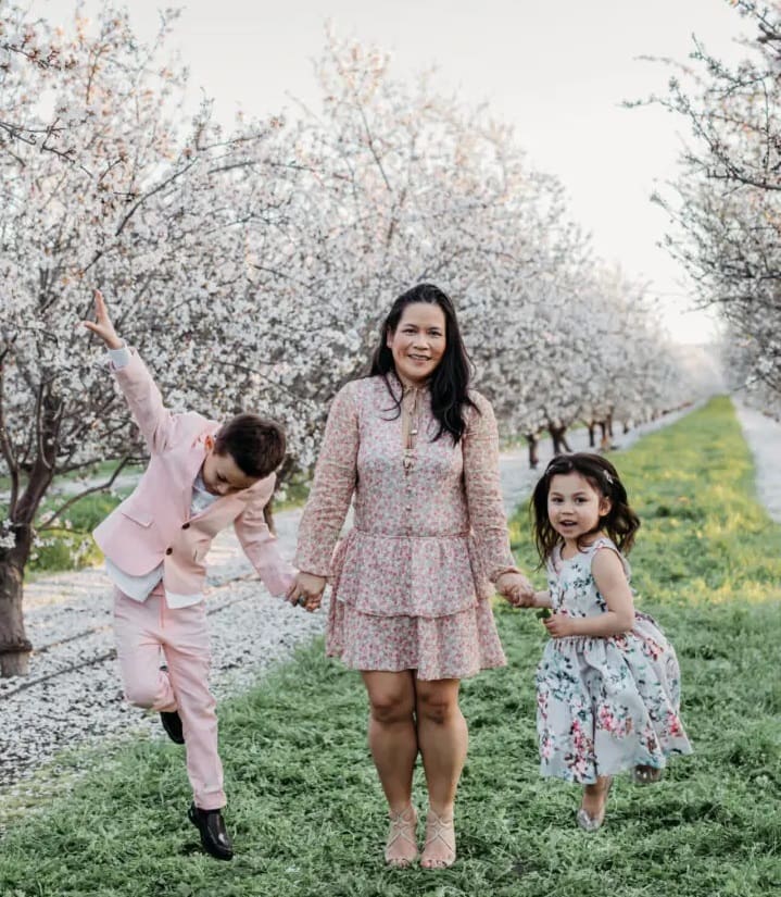 A woman and two children are holding hands.