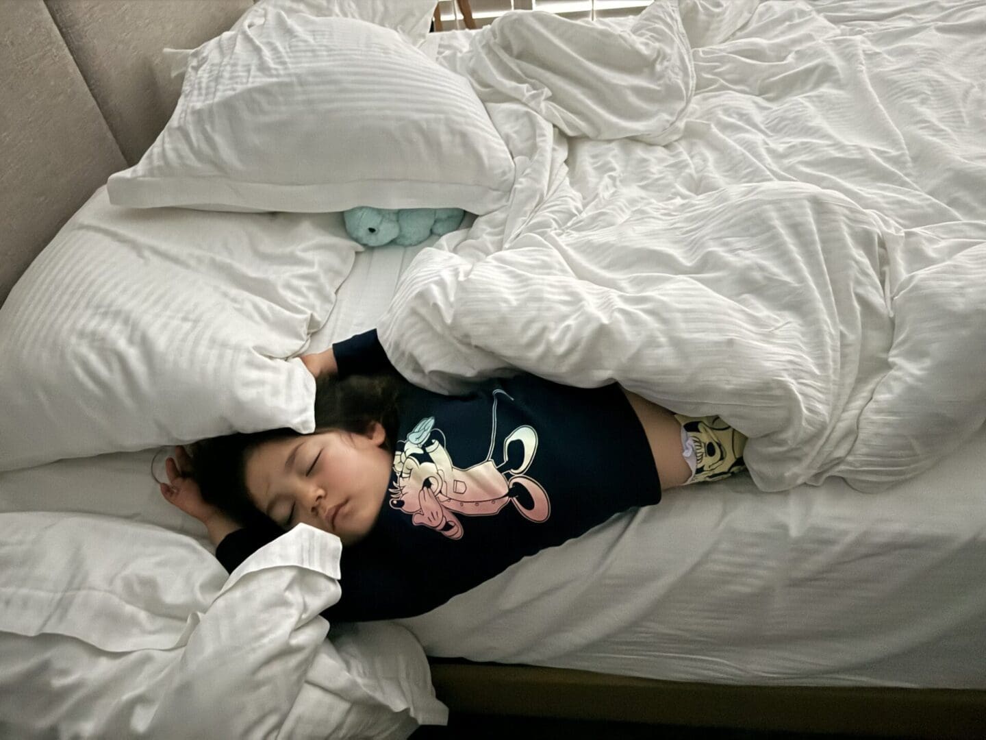 A child is laying in bed with pillows.