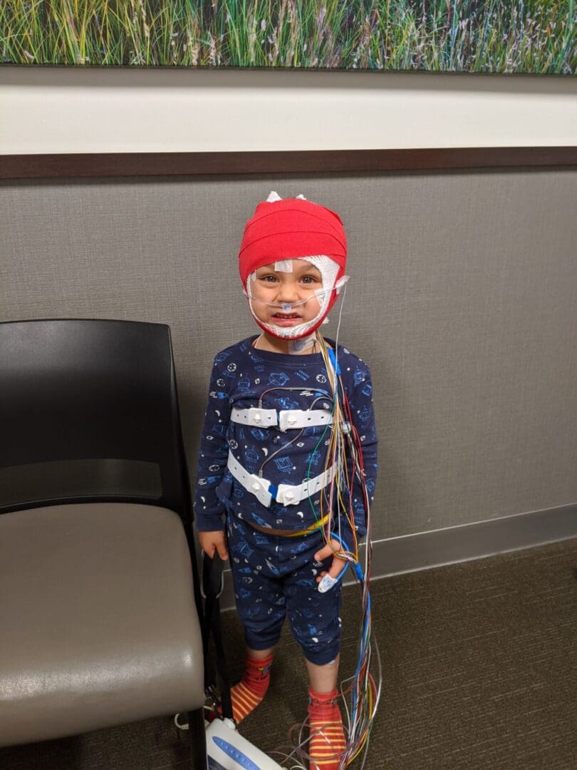 A young boy wearing a red hat and holding a stick.