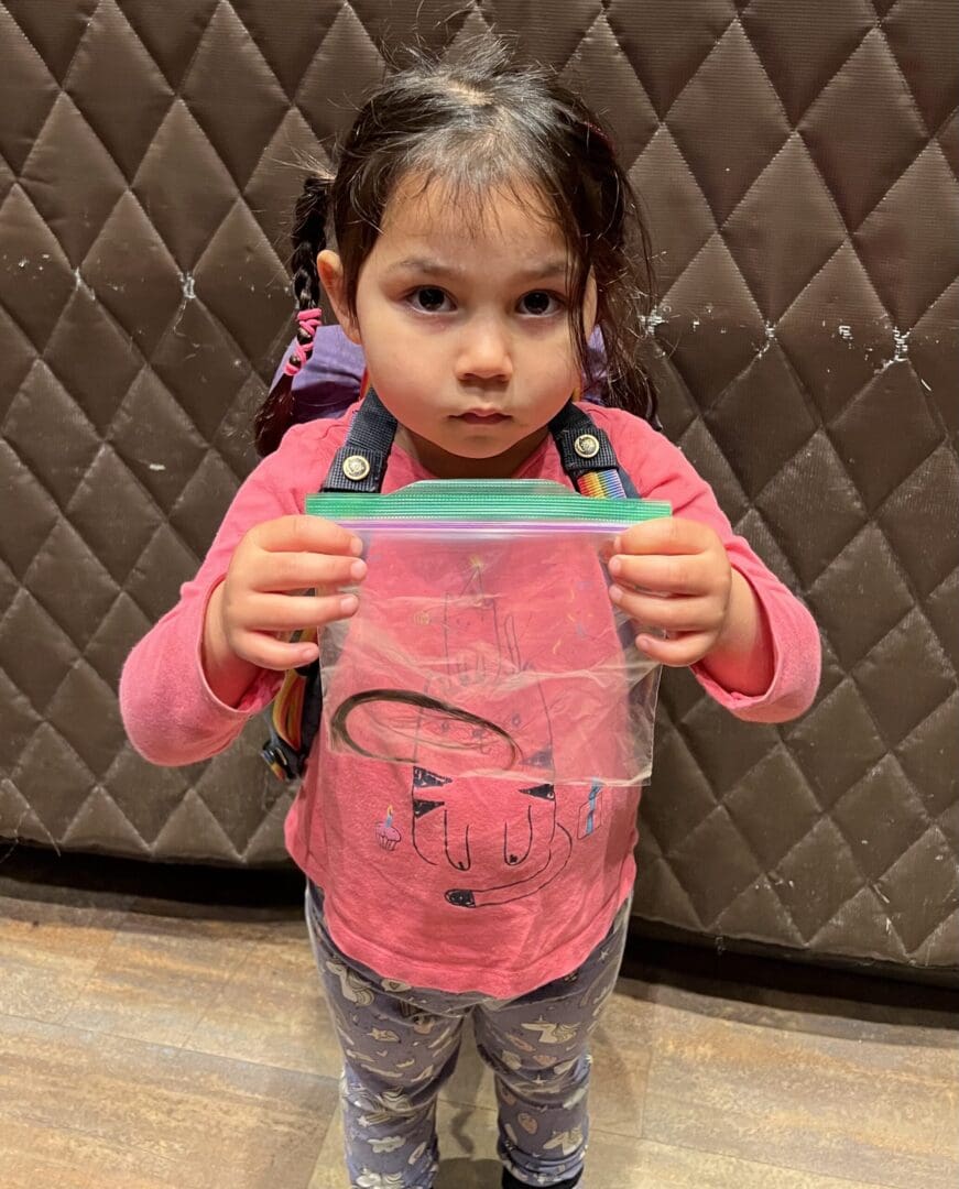 Girl holding a bag with a hair tie.