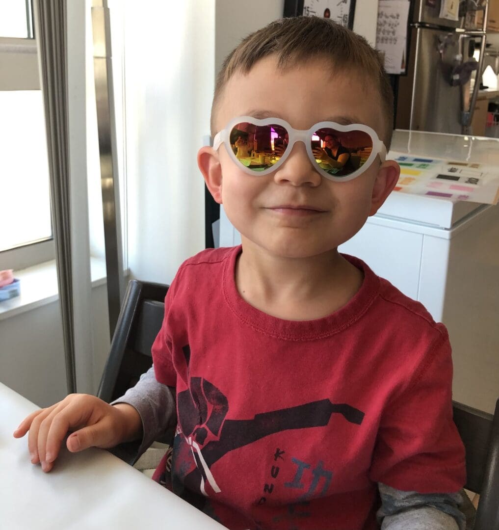 Toddler wearing heart-shaped sunglasses.